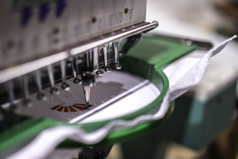 Brodeuse professionnelle dans un atelier textile réalisant une broderie d'un logo